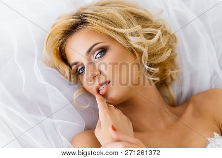 A Bride With Hairstyle And Make Up Lying On Her Dress. A Portrait Of Beautiful Girl Lying On Fatin C