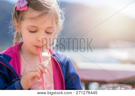 Cute Little Caucasian Girl Drinking Fruit Juice Through The Straw In Summer