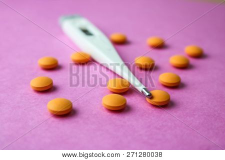 Small Medical Pharmacetic Round Pills, Vitamins, Drugs And Electronic Digital Thermometer On A Pink 
