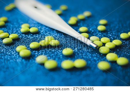 Small Medical Pharmacetic Round Tablets, Vitamins, Drugs And Electronic Digital Thermometer On A Blu