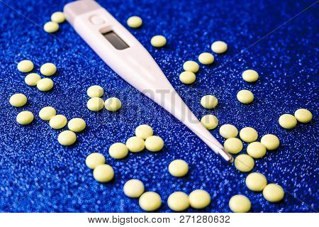 Small Medical Pharmacetic Round Tablets, Vitamins, Drugs And Electronic Digital Thermometer On A Blu