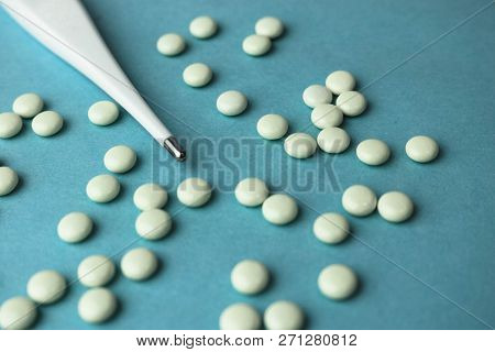 Small Medical Pharmacetic Round Tablets, Vitamins, Drugs And Electronic Digital Thermometer On A Blu