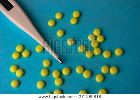 Small Medical Pharmacetic Round Tablets, Vitamins, Drugs And Electronic Digital Thermometer On A Blu
