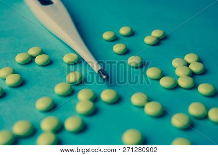 Small Medical Pharmacetic Round Tablets, Vitamins, Drugs And Electronic Digital Thermometer On A Blu