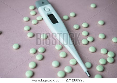 Small Medical Pharmacetic Round Pills, Vitamins, Drugs And Electronic Digital Thermometer On A Pink 