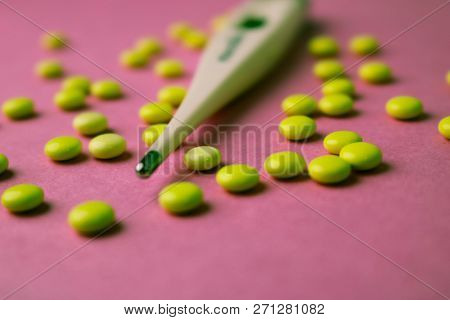 Small Medical Pharmacetic Round Pills, Vitamins, Drugs And Electronic Digital Thermometer On A Pink 