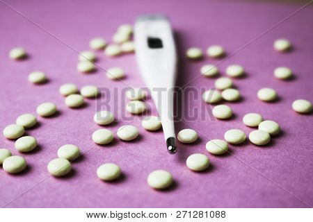 Small Medical Pharmacetic Round Pills, Vitamins, Drugs And Electronic Digital Thermometer On A Pink 