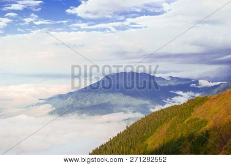 landscape - view from the mountain pass on a sunny day to the valley hidden by low clouds