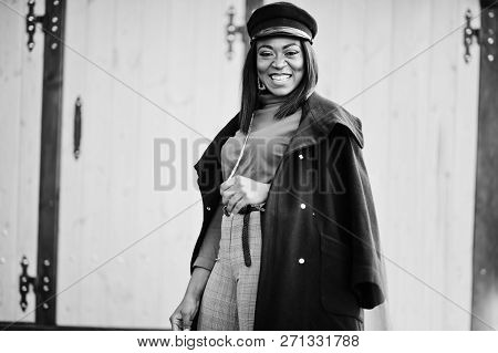 African American Fashion Girl In Coat And Newsboy Cap Posed At Street.
