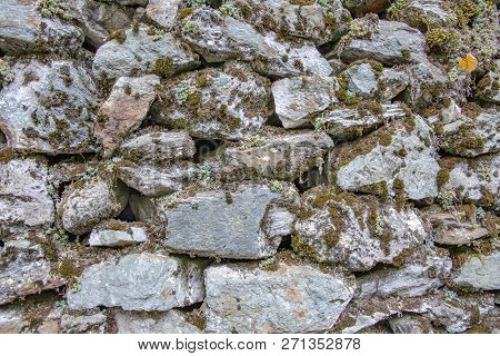 A Wall Of Masonry Stones Of Various Shapes Covered With Lichen, Moss And Sacculents. Greece