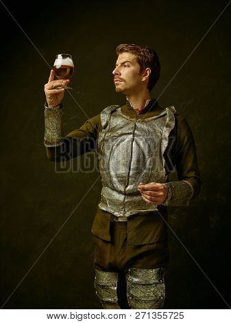 Medieval Knight With Beer On Dark Studio Background. Portrait In Low Key Of Brutal Man In Tradishion