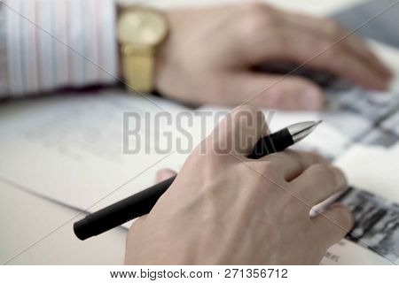 Mens Hands With Gold Watches Hold A Writing Pen Over The Paper.