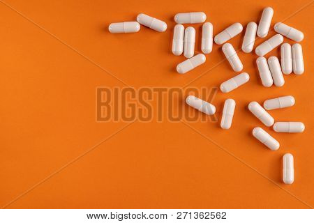 Medical Capsules And Pills On A Orange Background, Close-up, Top View, With Copy Space.