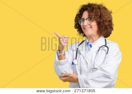 Middle ager senior doctor woman over isolated background Looking proud, smiling doing thumbs up gesture to the side