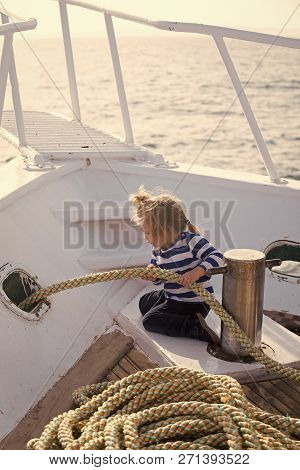 Yachting And Sailing Concept. Baby Care And Childhood. Little Child Sitting And Berthing Rope On Whi