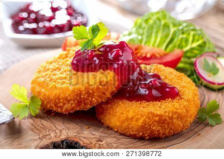 Breaded And Baked Camembert With Cranberry Sauce On Wooden Tabel .
