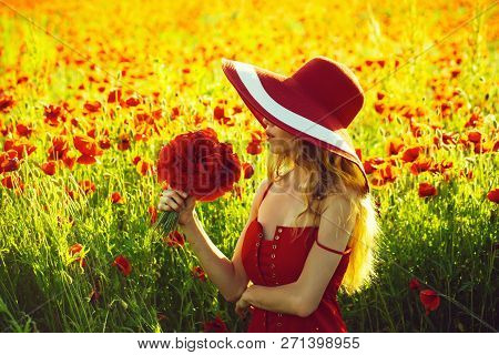 Pretty Girl With Long Curly Hair In Red Dress And Retro Hat Hold Flower Bouquet In Field Of Poppy Se