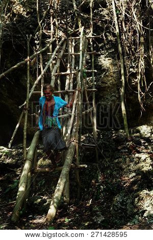 Lolits Village, Espiritu Santo Island / Vanuatu - Aug 10 2016 : Young Woman Climbing A Large Rock St