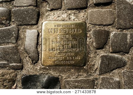 BERLIN, GERMANY - MAY 24, 2018: A Stolperstein, a golden cube with the name and life dates of a victim of nazi extermination, in the pavement of a street in the Charlottenburg district of Berlin