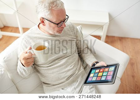 automation, internet of things and technology concept - senior man with smart home icons on tablet computer drinking tea
