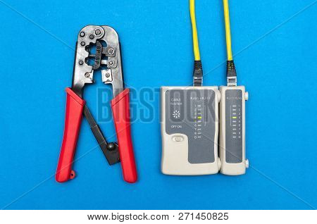 Cripmer Tool And Network Cable Tester Isolated On The Blue Background. Network Maitenance Background