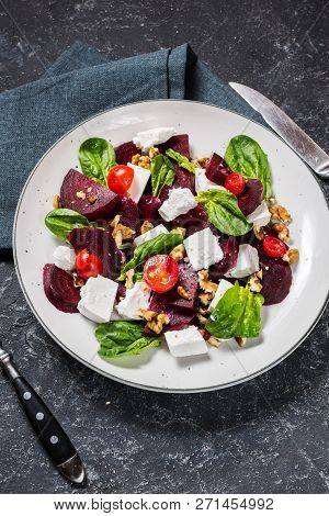 Dish With A Salad Of Feta, Beetroot, Cherry Tomatoes And Walnuts On A Stone Background.