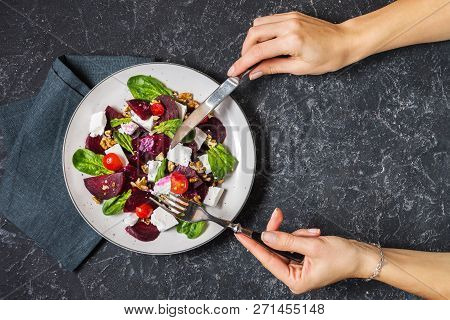 Dish With A Salad Of Feta, Beetroot, Cherry Tomatoes And Walnuts On A Stone Background. Female Hands