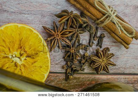 Hot Mulled Wine Drink With Lemon, Apple, Cinnamon, Anise And Other Spices In A Glass Cup Between Fir
