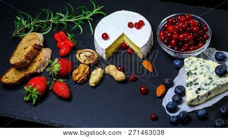Assorted Cheeses Onon Shale Board Plate Camembert Or Brie Cheese, Walnuts, Bread, Fruits And Berries