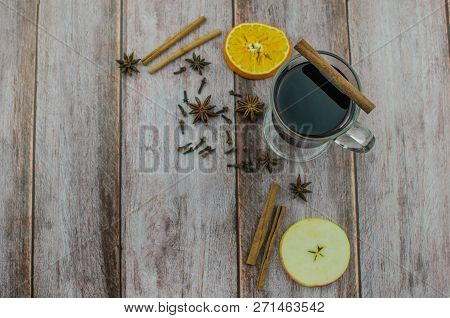 Hot Mulled Wine Drink With Lemon, Apple, Cinnamon, Anise And Other Spices In A Glass Cup Between Fir