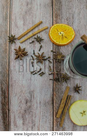 Hot Mulled Wine Drink With Lemon, Apple, Cinnamon, Anise And Other Spices In A Glass Cup Between Fir