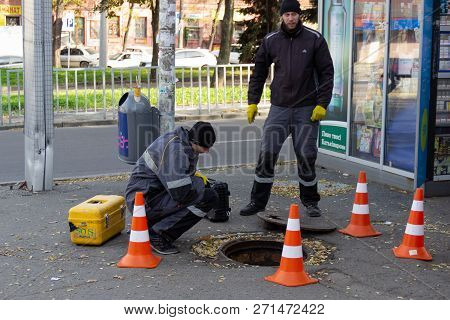 Dnipro, Ukraine - November 1, 2018: Employees Of A Telephone Company Near An Open Underground Hatch 