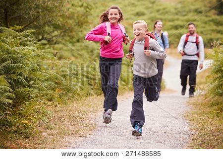 Children running ahead of parents, walking on a country path during a family camping trip, front view, close up