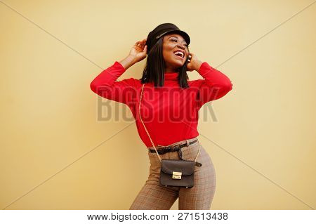African American Fashion Girl With Newsboy Cap Posed Against Yellow Background.