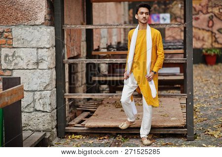 Indian Stylish Man In Yellow Traditional Clothes With White Scarf Posed Outdoor.