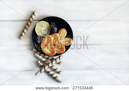 Sweet-staff With Slice Of Lemon And Frozen Berries On The Black Round Plate And White Wooden Table.