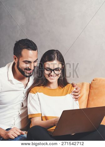 Attractive Long-haired Girl In Pullover Wearing Glasses Sitting With Her Multicultural Bearded Boyfr