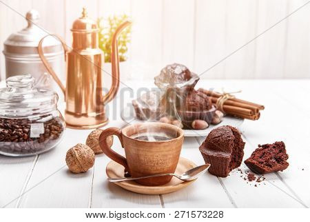 Coffee in clay cup with chocolate muffin on white wooden board in rustic style.