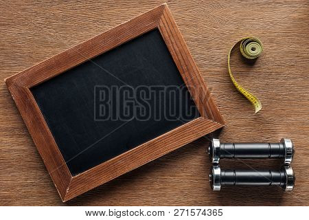 Blank Wooden Chalk Board, Measuring Tape And Dumbbells, Dieting And Healthy Lifesyle Concept