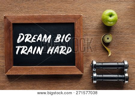 Apple, Dumbbells, Measuring Tape And Wooden Chalk Board With Dream Big Train Hard Quote, Dieting And