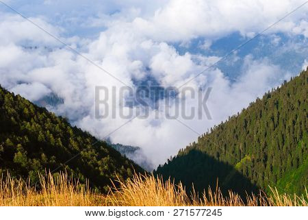 Landscape - View From The Mountain Pass On A Sunny Day To The Valley Hidden By Low Clouds