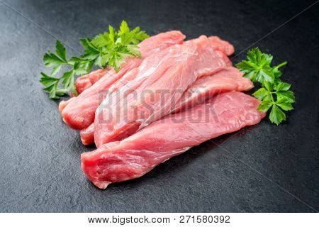 Raw suckling pig fillet offered on a black slate slab as closeup 
