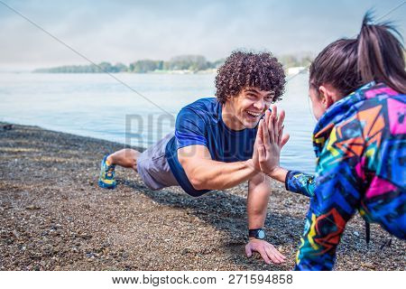 Happy Sporty Couple Giving High Five To Each Other While Doing Push Up Together Outdoors
