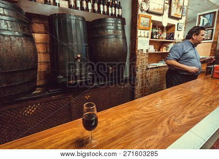Cordoba, Spaine - Nov 18: Glass Of Red Wine, Barrels And Bartender Of The Traditional Tapas Bar Or R
