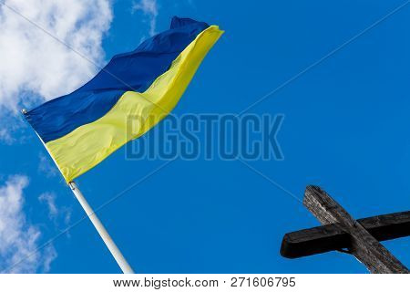 Khust, Ukraine - May 15, 2015: Ukrainian Flag Waiving Above The Wooden Cross In Khust, Ukraine