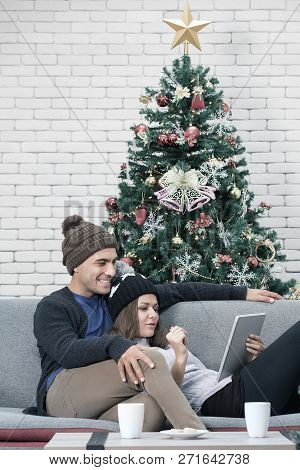 Young Cacausian Couple Lean Relax On The Sofa Look At Something On Tablet Device 
On The Back There 
