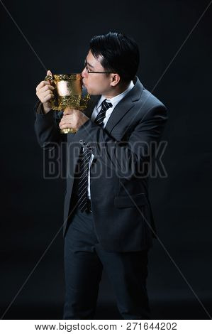 Asian Man In Formal Suit Holding And Kissing Golden Trophy Cup, Reward Of Target Achievement Winner,
