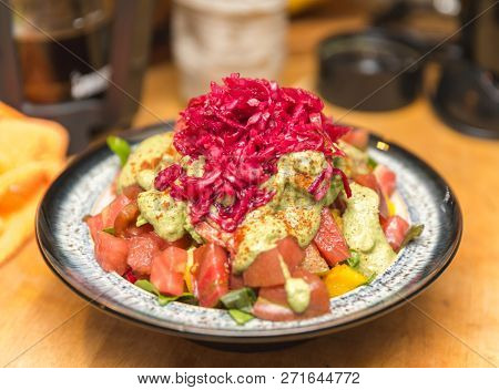 Raw, Organic, Vegan Meal Prepared With Tomatoes, Peppers, Avocado Paste, Pickled Cabbage, And Spices