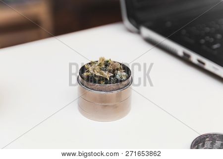 Steel Grinder With Green Cannabis Flower (buds) Inside. Laptop In Background.