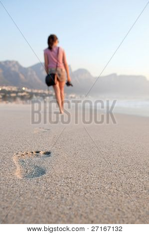 ragazza camminare a piedi nudi lascia la sua impronta nella sabbia.